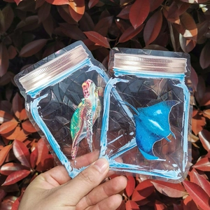 Hand holding holographic sea turtle and manta ray jar window stickers with rainbow prism effect