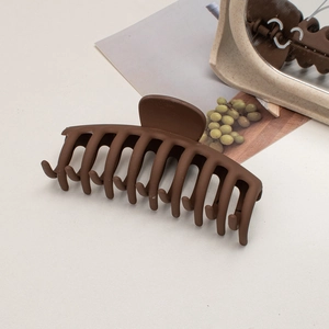 Detailed view of large matte dark brown hair claw clip with its reflection in a mirror
