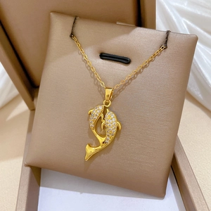 Close-up of golden necklace featuring crystal-studded dual dolphin pendants on a velvet pad
