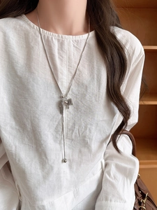 Detail of silver long tassel pendant necklace on model with polished snake chain