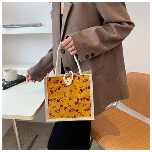 Close-up of yellow floral canvas handbag with white button and rope handles