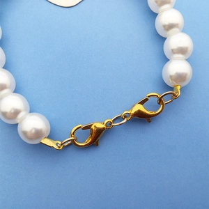 Detail of white faux pearls connected by a gold-tone lobster clasp for DIY necklaces