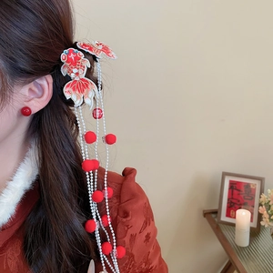 Detailed close-up of embroidered koi fish hair clip with red tassels and soft bead strands