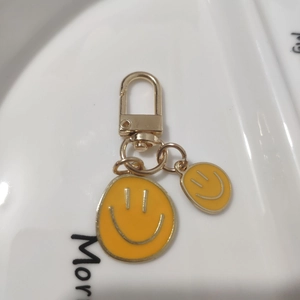Detailed close-up of golden alloy keychain with two yellow enamel smiley face charms