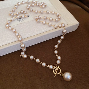 Détail d'un collier de perles élégant avec fermoir à bascule doré et grand pendentif