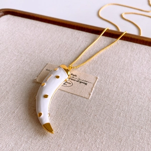 Detail of retro crescent moon necklace with gold dots on warm beige fabric