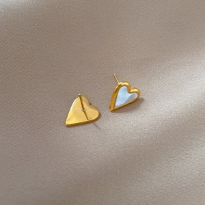 Macro shot of titanium steel heart studs with white shell inlay and gold-plated borders