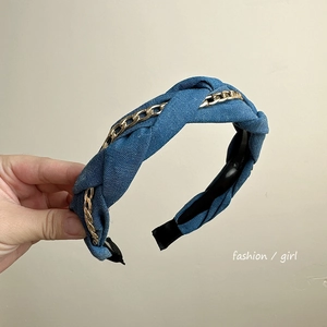 Detail of blue denim headband featuring intertwined gold chain and knotted bow design