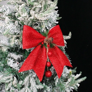 Christmas red glitter bow with pine cones and berries hanging on a snowy tree