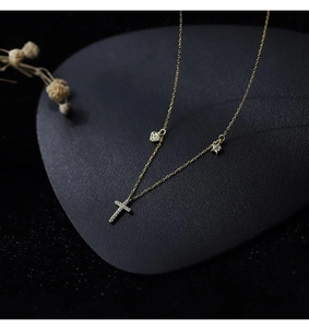 Close-up of gold clavicle necklace featuring sparkling cross, heart, and star pendants