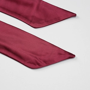Detail of burgundy satin dress tie-back straps with sharp triangular cut and silk sheen