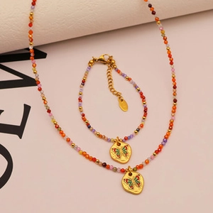Macro shot of colorful beaded jewelry set with gold butterfly pendants on soft background