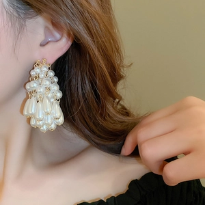 Gros plan d'élégantes boucles d'oreilles pendantes en perles et diamants sur un mannequin