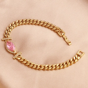Detail of gold-plated Cuban bracelet with pink marquise zircon and silk backdrop