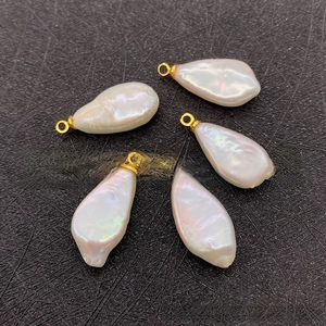 Close-up of five irregular baroque freshwater pearl pendants with gold loops on black base