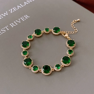Detail of vintage gold plated bracelet with emerald green stones and white zircons
