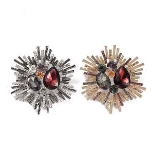 Detailed macro view of baroque sunburst brooches featuring intricate crystal and gemstone inlay