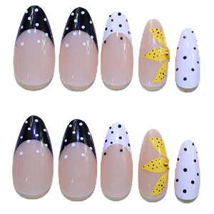 Detail view of almond-shaped press-on nails with French dots and yellow floral art