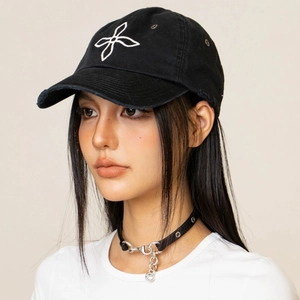 Close-up of distressed black denim baseball cap with white cross embroidery detail