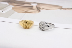 Detail of Cupid angel embossed rings in gold and silver finish on textured surface