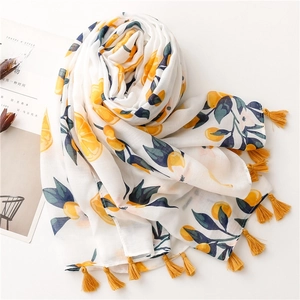 Detailed view of white scarf with vibrant orange prints and bright yellow tassels