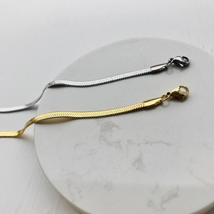 Close-up of gold and silver snake bone chain lobster clasps on marble base