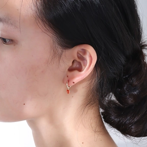 Close-up of red enamel heart earrings with gold edges on model's ear showing texture