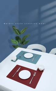 Close-up of Nordic style faux leather placemats and coasters set in Morandi blue and red