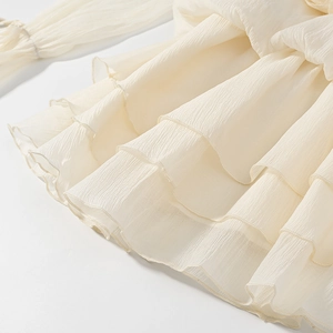Close-up of layered ruffle details on cream chiffon fabric with a pleated texture