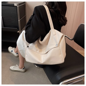 Detail of off-white oversized tote bag showing litchi grain texture and silver metal buckle