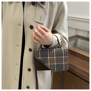 Detail of vintage plaid handbag with brown leather trim and gold metal accent