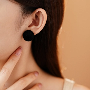 Close-up of black velvet round stud earring on model with elegant profile view