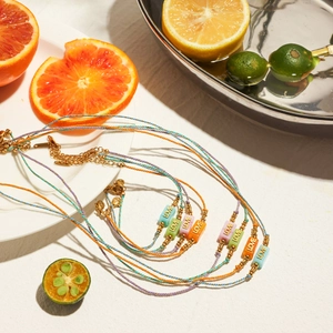 Colorful woven cord necklaces with gold LOVE pendant beads in a summer beach setting