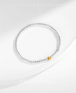 Close-up of s925 silver beaded bracelet with a single matte gold bead on white backdrop