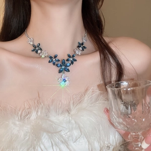 Close-up of elegant zircon flower necklace with blue crystals on female model