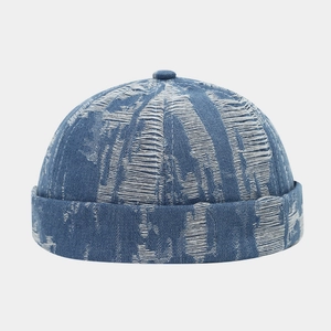 Macro detail of distressed denim docker cap showing white frayed threads and blue texture