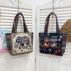 Detail view of ethnic canvas totes with elephant and owl embroidery and woven handles