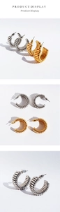 Macro shot of wavy textured C-shaped hoop earrings in gold and silver finishes