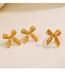 Macro detail of gold plated bow earrings with striped texture and metallic luster