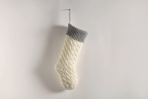 Close-up of cream knitted Christmas stocking with grey cuff and cable knit texture