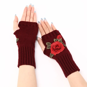 Detailed close-up of wine red knitted fingerless gloves featuring 3D rose flower embroidery
