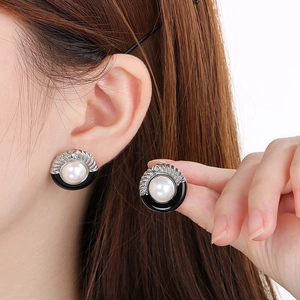 Detailed view of silver stainless steel earrings with black enamel and pearl inlay