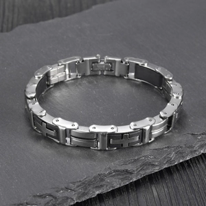 Classic silver stainless steel and black silicone cross bracelet on a textured stone base
