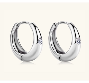 Close-up of silver U-shaped moissanite earrings with a single clear round zircon