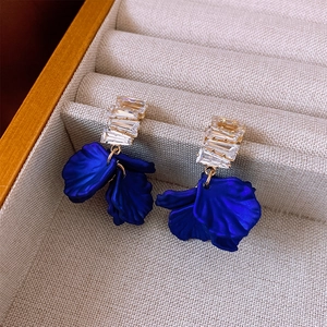 Detailed close-up of blue petal earrings with zircon studs and gold plating on fabric
