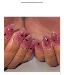 Dettaglio di unghie finte a mandorla con sfumatura rosa-viola, stelle e glitter lucenti