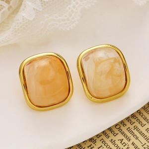 Vue détaillée de boucles d'oreilles carrées plaquées or avec texture en résine d'ambre