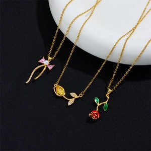 Three elegant gold flower necklaces with tulip, rose, and bow charms on black background