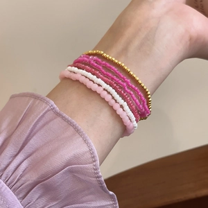 Close-up of bohemian style layered bead bracelets in pink, white, and rose gold tones