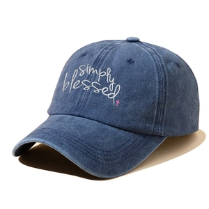 Detailed close-up of simply blessed white embroidery on navy blue washed denim cap